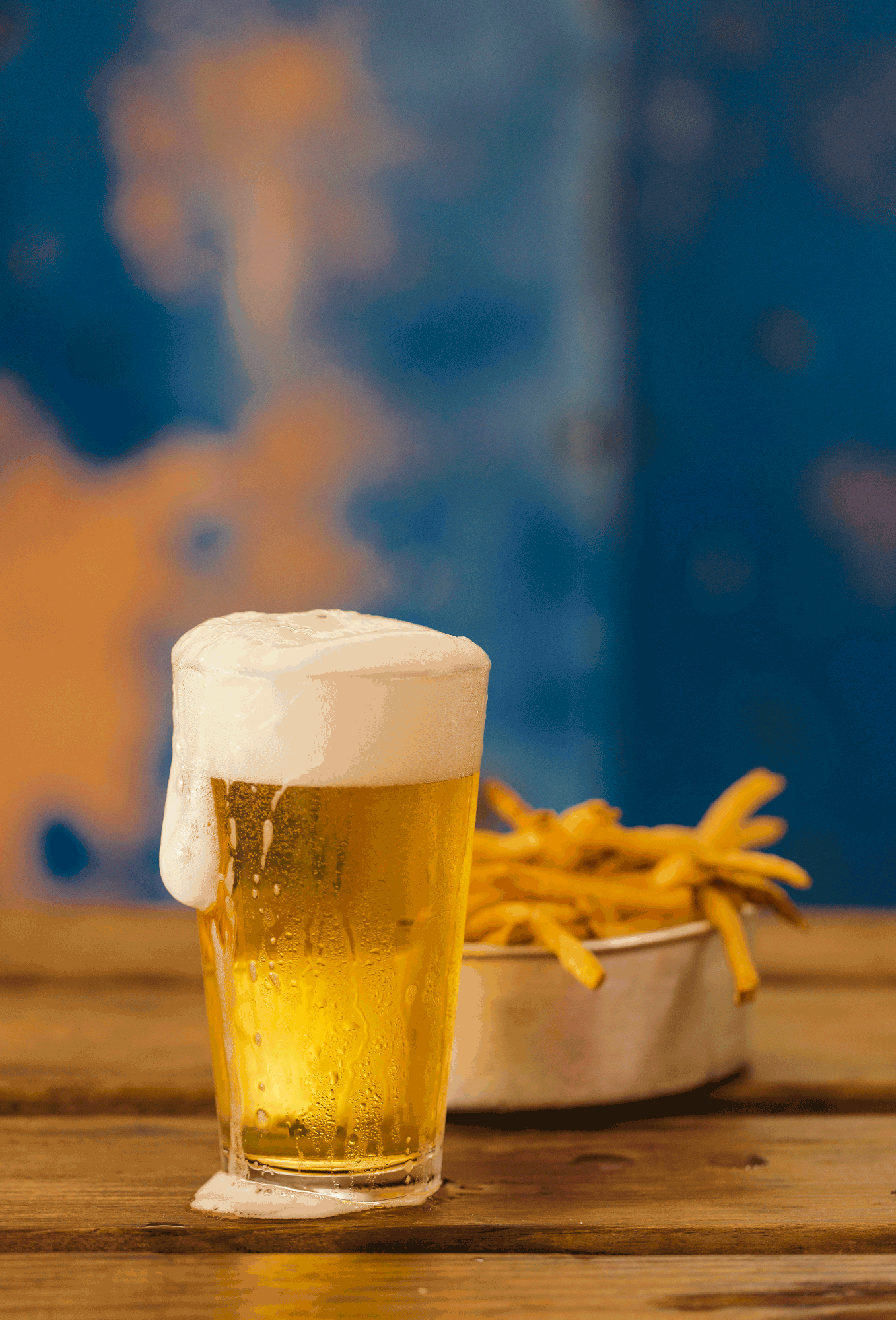 A Lone-Pint Brewery cold class of draft beer in front of a bowl of fries, photographed by Todd Spoth
