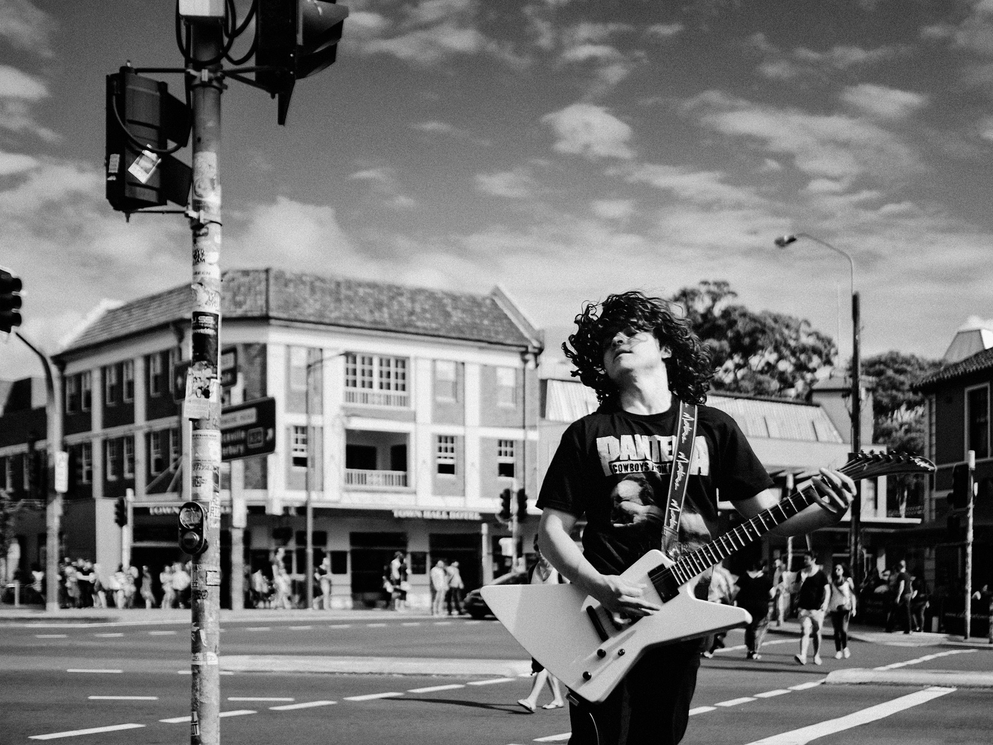 A boy plays metal music in a Pantera t-shirt on the street in Sydney, Australia, photographed by Todd Spoth.