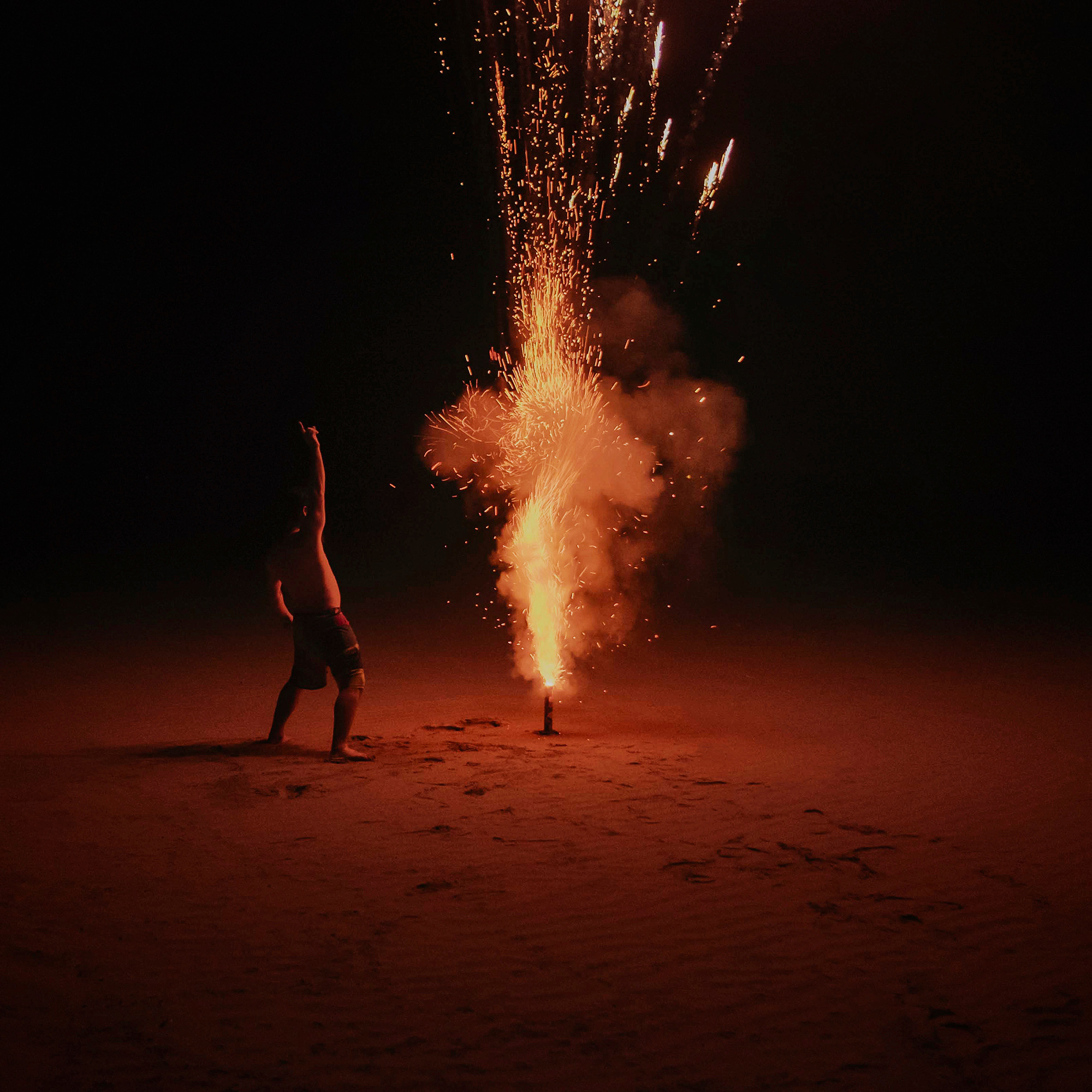 A man lights a firework on the beach on South Padre Island, Texas, photographed by commercial photographer, Todd Spoth.
