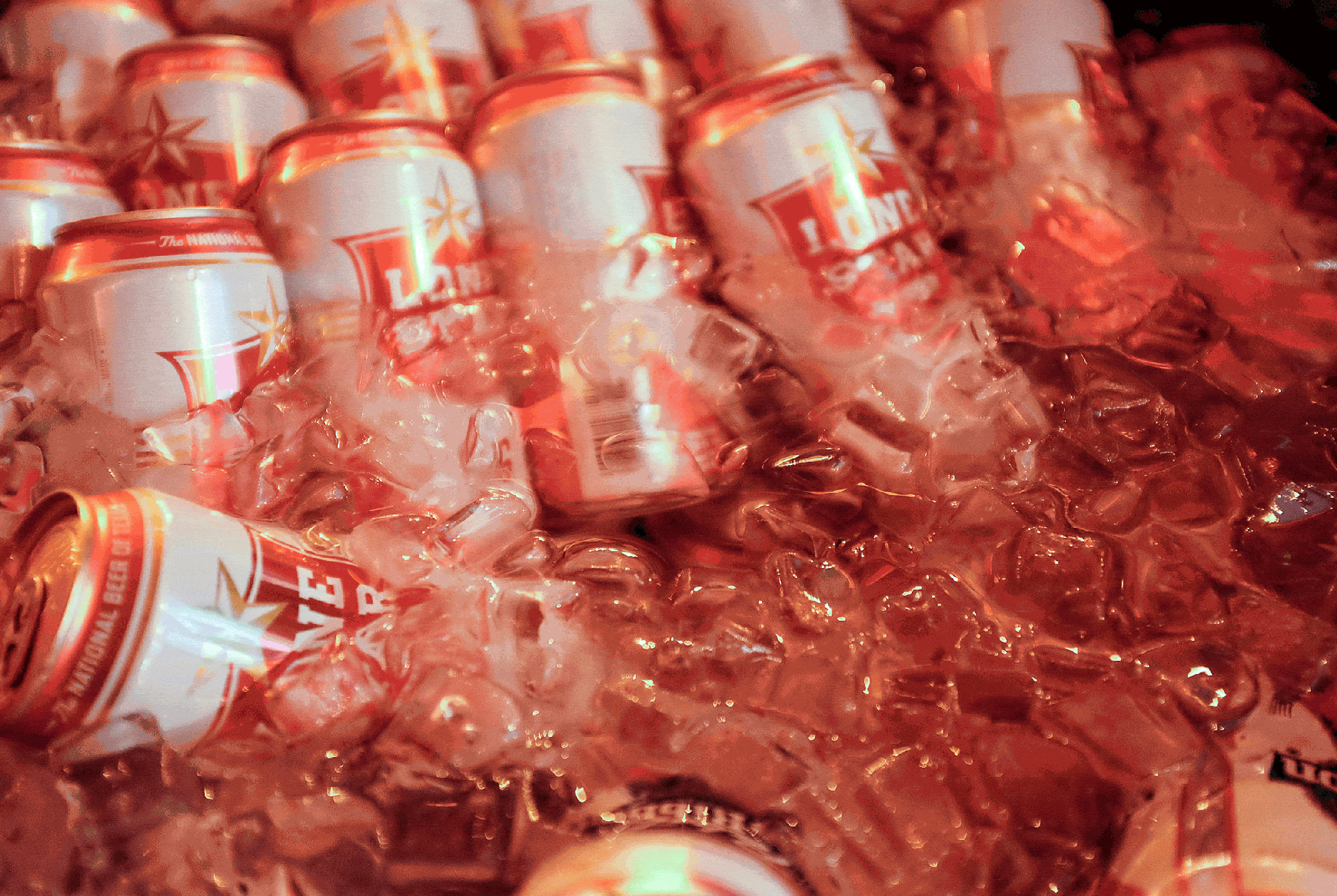 A bartender pulls a Lonestar beer from a cooler full of beer and ice, photographed by Todd Spoth